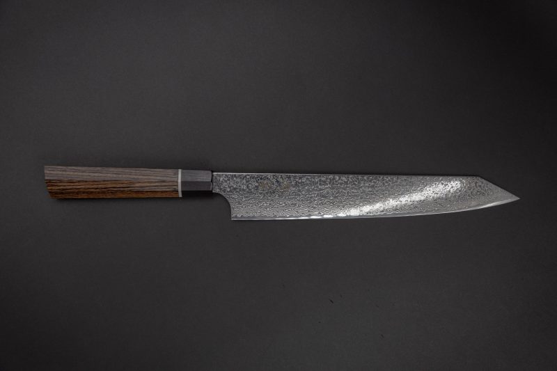 Ein Kochmesser im japanischen Stil mit einer gemusterten Stahlklinge und einem dunklen Holzgriff auf einem schlichten dunklen Hintergrund.