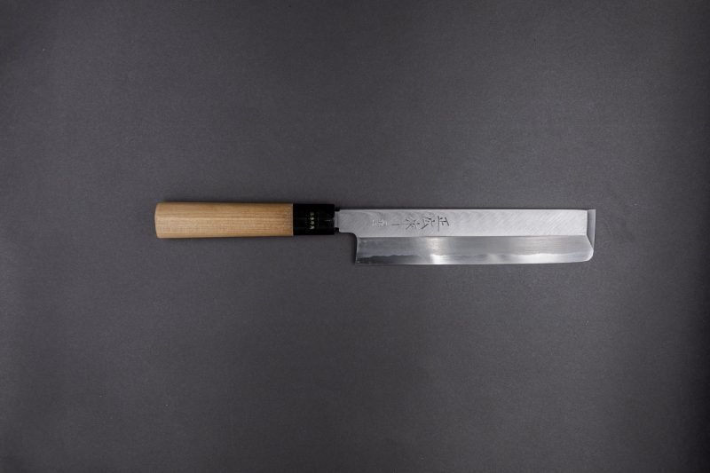 Ein Küchenmesser im japanischen Stil mit gerader Klinge und Holzgriff ist horizontal auf einem dunkelgrauen Hintergrund platziert.